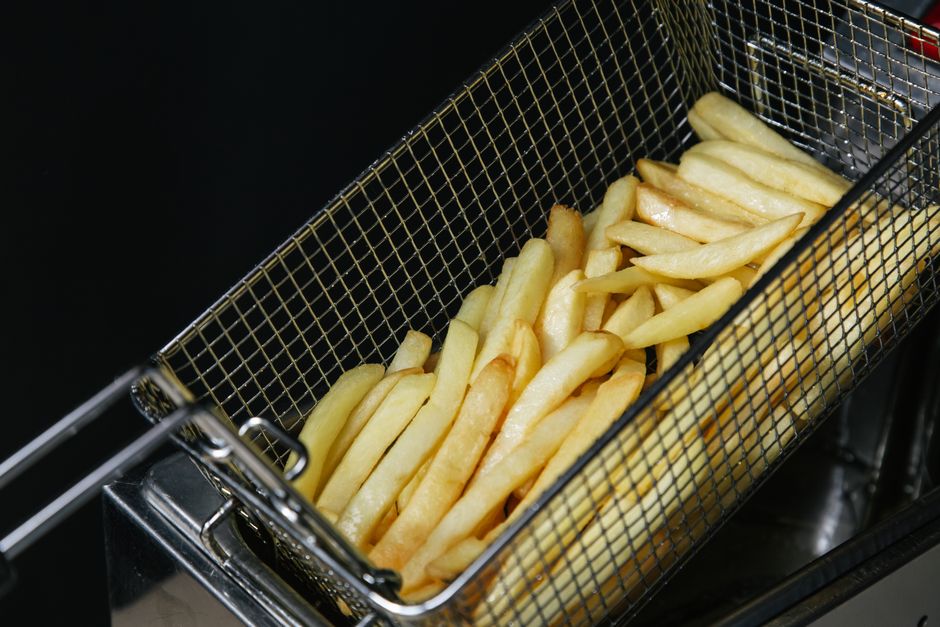 Crispy French fries in a metal fryer basket