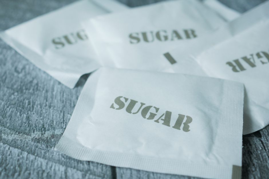 Small paper sweetener packets scattered on a wooden surface