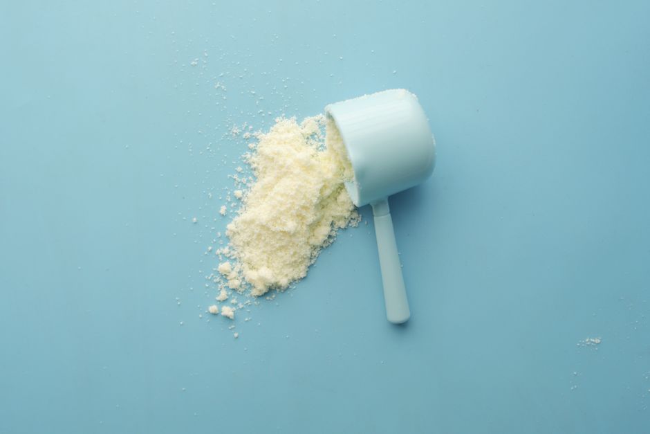 A scoop of white protein powder on a blue background