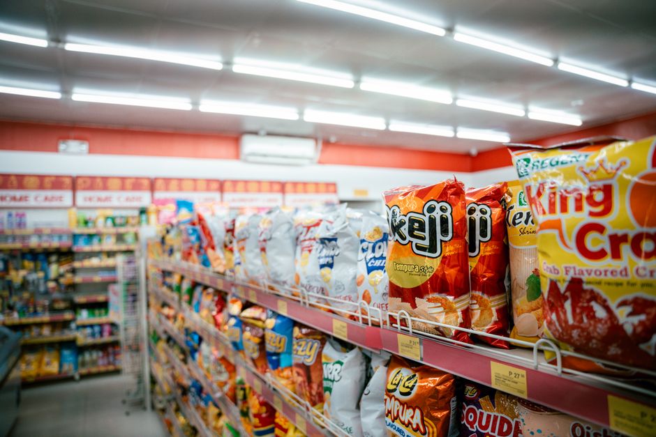 Wide shot of vibrant snack aisle in a supermarket with various chip bags on display