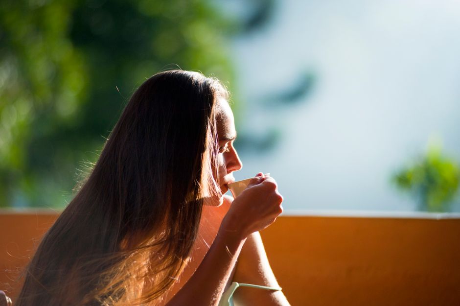 A woman relaxing at home while holding a warm cup of tea