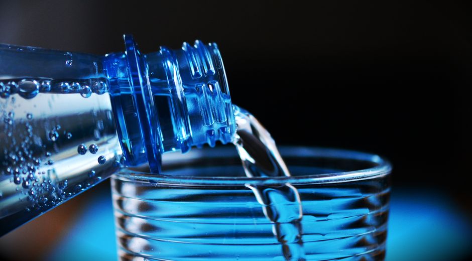 A glass being filled with water from a bottle