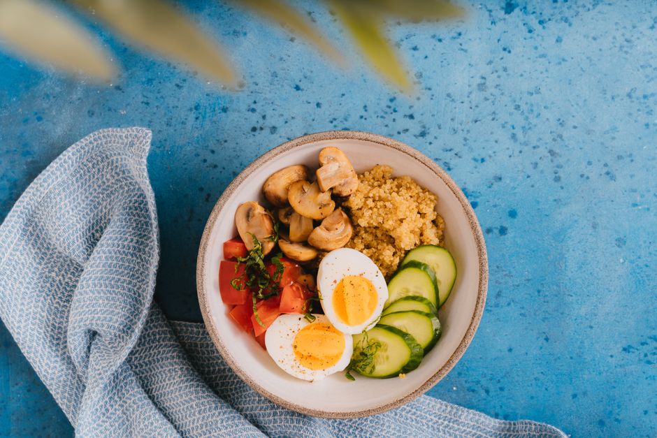 A bowl of quinoa with eggs, mushrooms, tomatoes, and cucumber