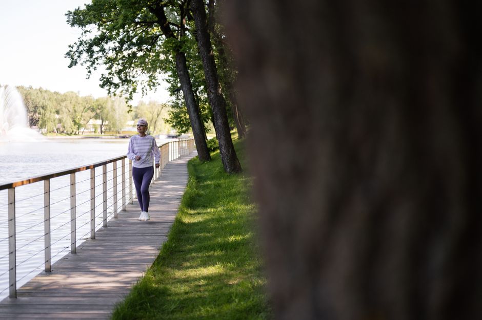 An older woman jogging outdoors near trees