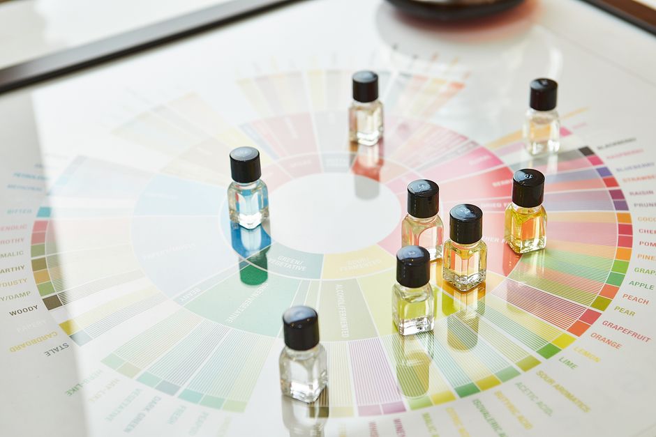 Small glass vials of flavor compounds arranged on a colorful flavor wheel chart