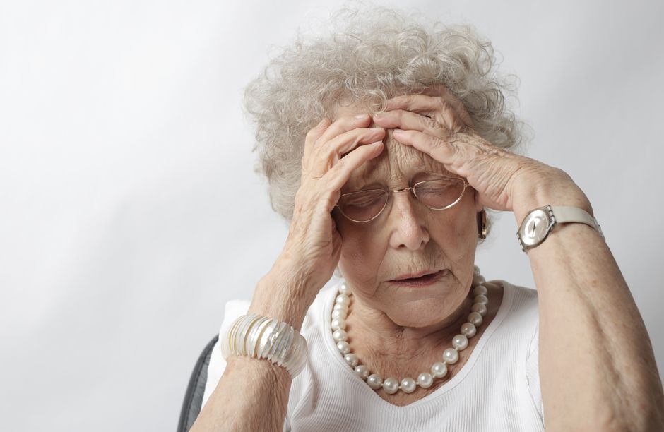 An older woman holding her head, appearing lightheaded