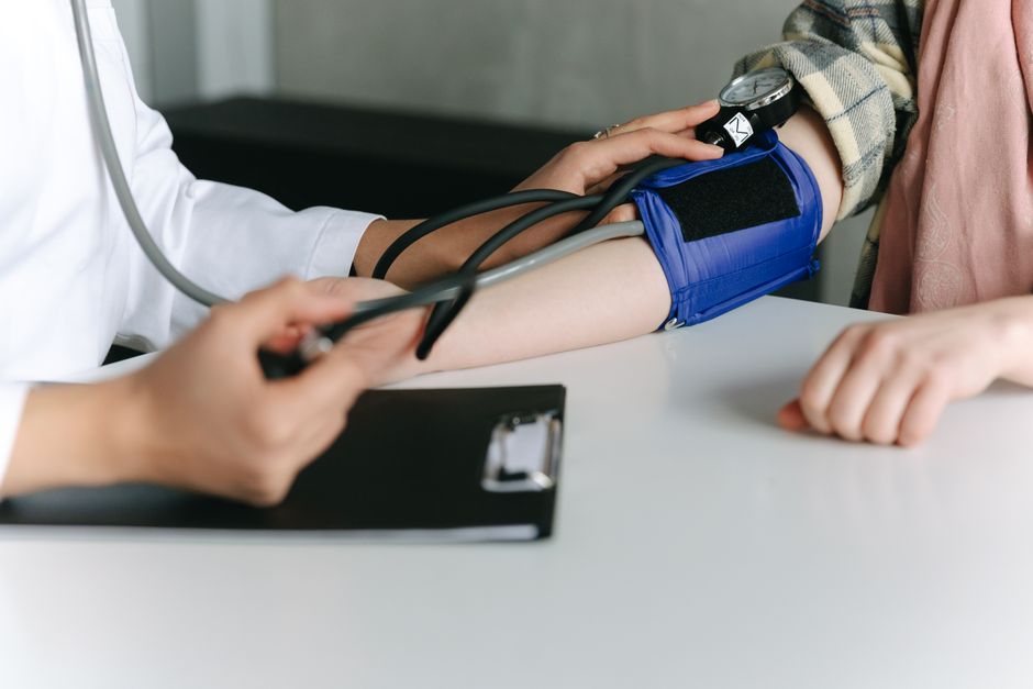 A healthcare worker measuring a patient's blood pressure with a cuff and stethoscope