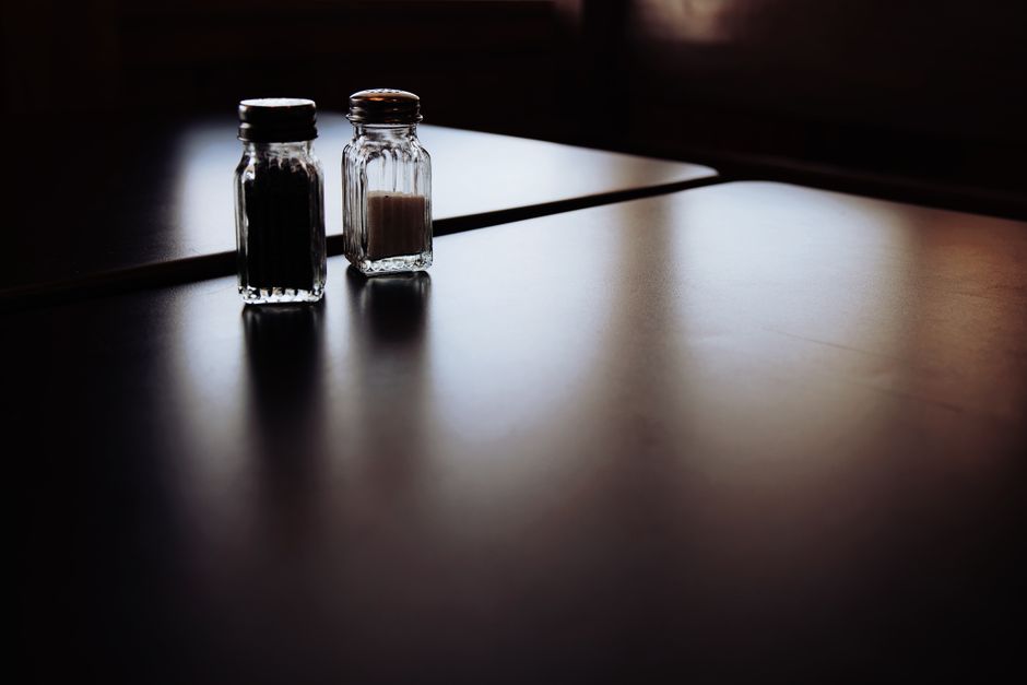 A moody still life of salt and pepper shakers on a dimly lit table
