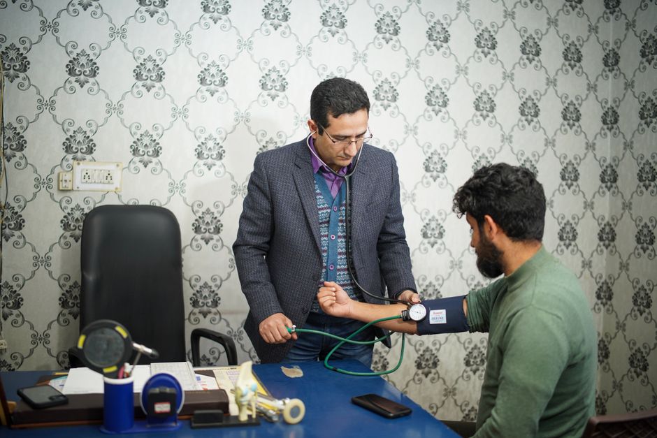 A doctor taking a patient's blood pressure in a clinical setting